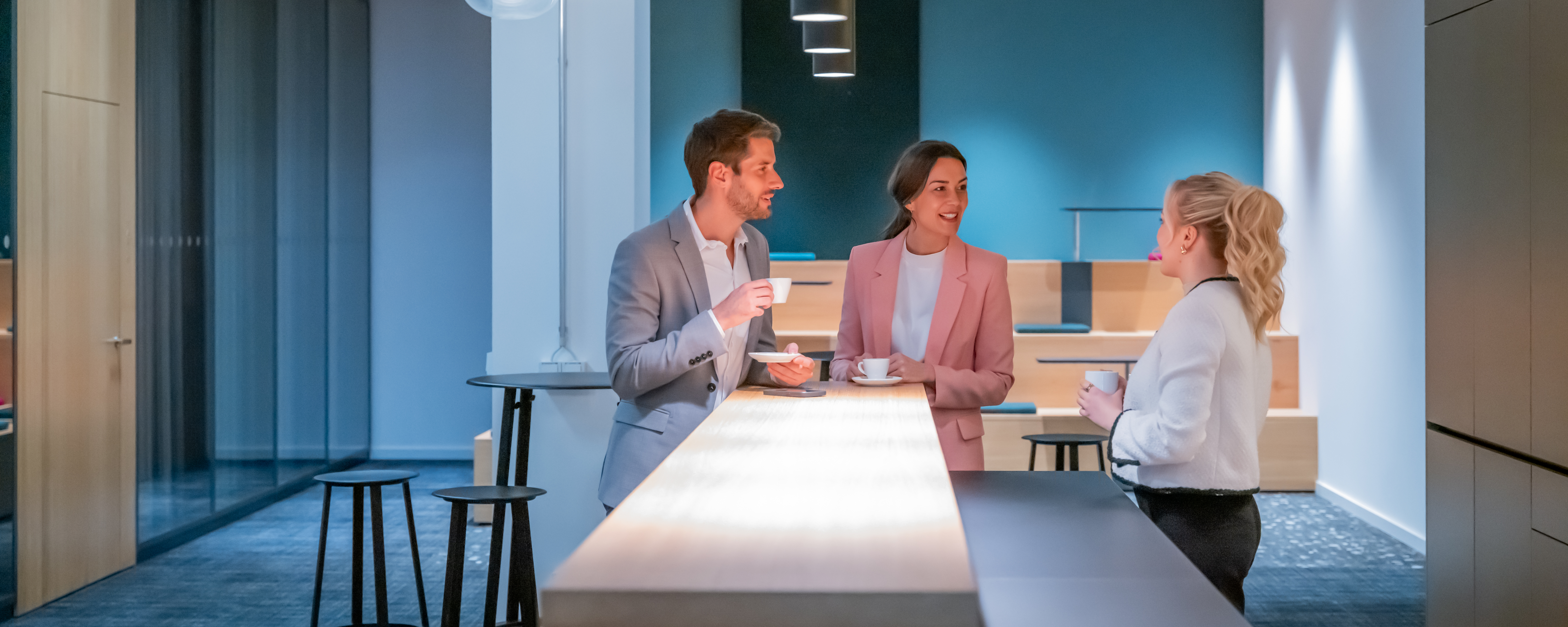 Drei Personen in Büro Kaffeeküche unterhalten sich